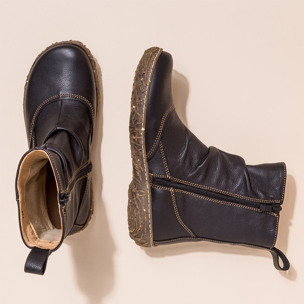 Top down view of a pair of El Naturalista black zip-up ankle boots with one boot lying on its side